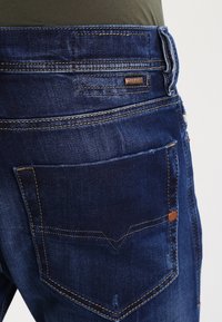 Mörkblå denimjeans med en klassisk femfickdesign, kontrastsömmar och en liten läderetikett på bakre midjan.