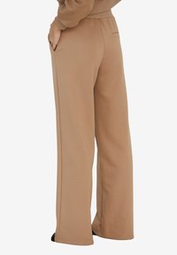 Beżowe, szerokie spodnie dresowe wykonane z miękkiego materiału. Posiadają boczne kieszenie oraz jedną tylną kieszeń. Elastyczny pas dla wygody.