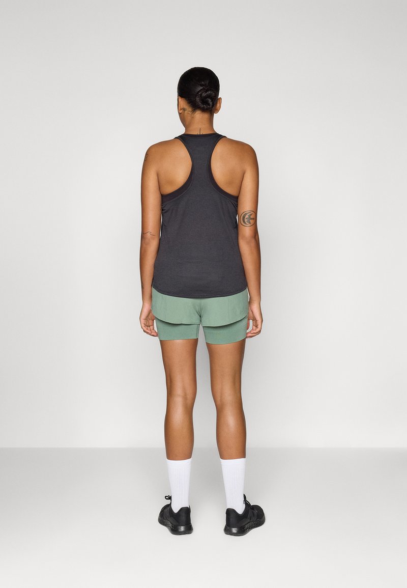 Camiseta sin mangas negra con diseño de espalda nadadora, combinada con pantalones cortos deportivos verdes. Incluye calcetines blancos y zapatillas negras.