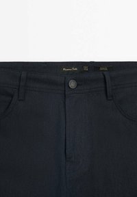 Dunkelblaue Slim-Fit-Jeans mit Frontknopf und Gürtelschlaufen, mit dem Markenlabel "Massimo Dutti" innen am Bund.