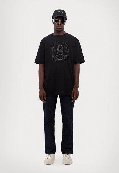 Črna bombažna majica s kratkimi rokavi in belim grafikonom, sproščen kroj. Združena z temnimi kavbojkami, čepico in belimi supergami.