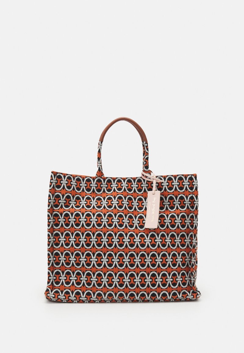 Tote tas gemaakt van geweven materiaal met een ingewikkeld geometrisch patroon in oranje, zwart en zilver, met bruine leren handvatten en een label.