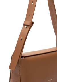 Borsa a tracolla in pelle marrone con design piatto, una larga tracolla e dettagli in metallo dorato. Presenta una texture liscia e cuciture precise.