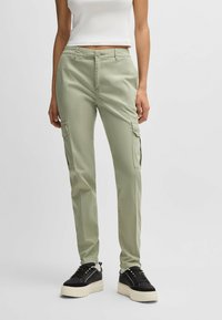 Ljusgröna cargobyxor i en bomullsblandning, med sidofickor, slim fit och slät framdel med knappstängning. Matchas med svarta sneakers.