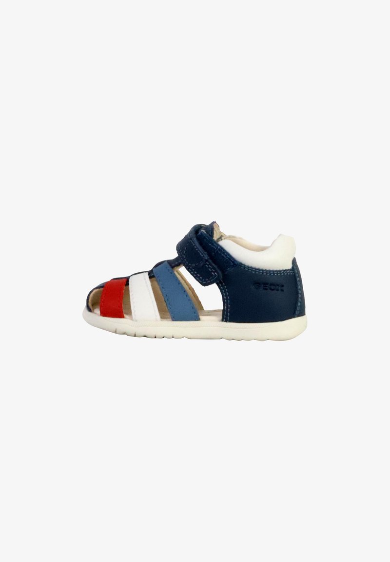 Sandale pour enfant en cuir bleu marine avec des accents rouges, blancs et bleus. Présente un design à bout ouvert, une sangle velcro et une semelle blanche flexible.