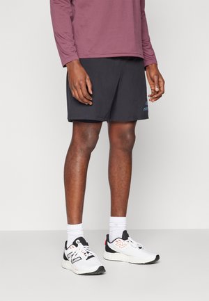 Black athletic shorts with a smooth texture and blue logo, paired with a maroon long-sleeve shirt and white sneakers with gray accents.