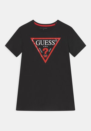 Melnas kokvilnas T-krekls ar sarkanu trīsstūrveida logotipu, kurā ir teksts "GUESS® U.S.A." un jautājuma zīme. Īsas piedurknes un apaļā kakla dizains.