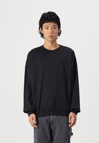 Black sweatshirt with long sleeves and ribbed neckline, made of soft textile. Features dropped shoulder seams and relaxed fit.