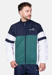 Giacca a vento Sergio Tacchini con design a blocchi di colore in blu navy, verde acqua e bianco, con chiusura a zip frontale e polsini elasticizzati.