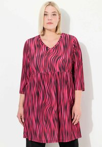 Pink V-pääntie mekko mustilla kiehuvilla kuvioilla, valmistettu kevyestä kankaasta. Ominaisuuksia ovat kolmen neljäsosan hihat ja muotoiltu vyötärö.