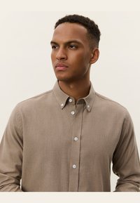 Lichtbruine button-up shirt van textuurstof, met een kraag, geborduurd logo en een knoopsluiting met contrasterende knopen.