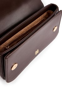 Braune Lederhandtasche, geöffnet, um das beige Innenfutter mit einem Reißverschlussfach und magnetischen Druckknopfverschlüssen an der Klappe zu zeigen.