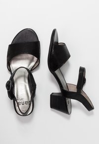 Svarta klackade sandaler med öppen tå och ankelrem. Slät läderöverdel, texturerad blockklack och metallisk innersula. Justerbar spänndetalj.