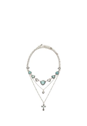 Zilverkleurige gelaagde ketting met turquoise hartvormige stenen, een kleine ovale hanger en een gedetailleerde kruis hanger op een witte achtergrond.