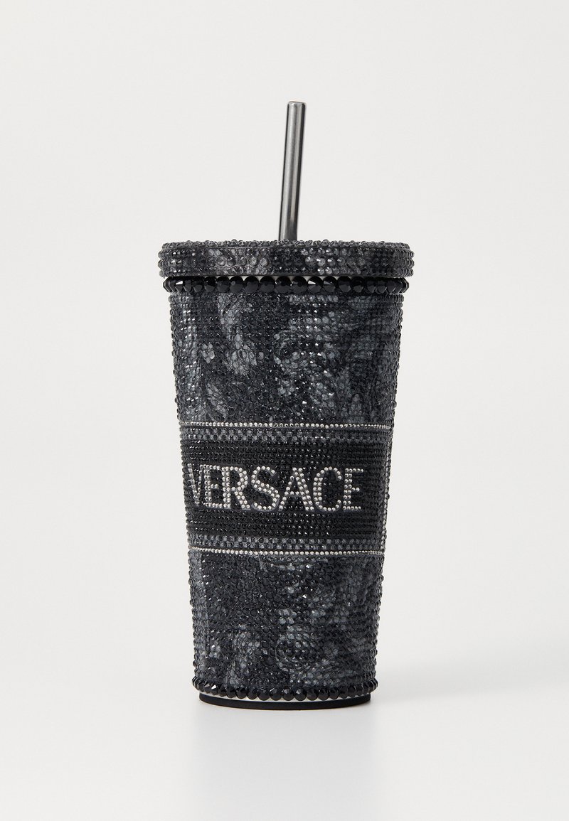 Tazza nera in strass con finitura testurizzata, dotata di un cinturino con logo Versace argentato e una cannuccia metallica. Base circolare e design conico.