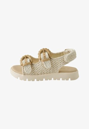 Beige geweven sandaal met twee decoratieve gespsluitingen en een dikke, geribbelde zool, ontworpen voor casual comfort en stijl.