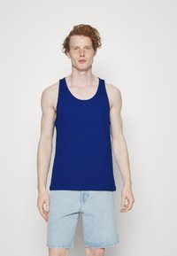 Top en coton bleu à encolure dégagée, sans manches et à coupe décontractée, associé à un short en denim clair.