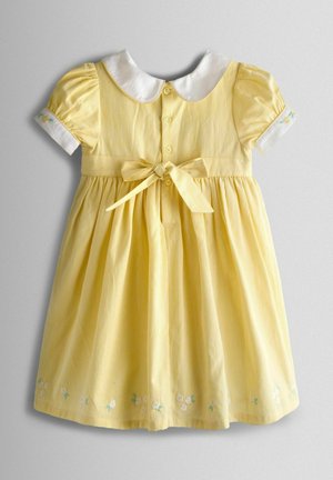 Gelb gestreiftes Kleid mit kurzen Puffärmeln, weißem Peter-Pan-Kragen, Stoffgürtel und Blumenstickerei am Saum. Mit Knopfverschluss.