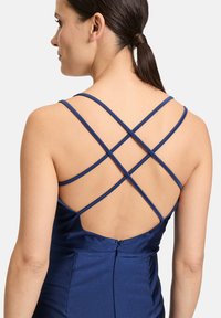 Marinblå satin klänning med en korslagd baksidedesign och en dold dragkedja. Slät textur och figurnära silhuett framhäver den övergripande stilen.