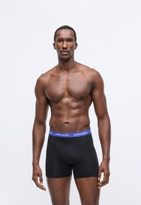 Fekete boxer alsónadrág kék elasztikus derékpánttal, rajta a "BJÖRN BORG" logóval. Sima textúra, testhezálló dizájn és combközép hosszúság.