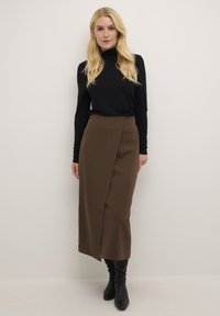 Černý dlouhý rukáv top sp paired s hnědou zavinovací sukní ke kolenům. Sukně má překrývací design v přední části a je vyrobena z měkké látky.