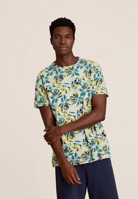 Korte mouwen shirt in lichtgroen met een bloemenpatroon in blauw, geel en groen. Casual pasvorm met ronde halslijn en zachte textuur.