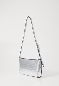 Sølv crossbody-veske med et elegant design, preget logomønster, justerbar stropp og glatt metallisk tekstur. Glidelås-lukking.