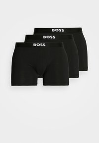 Un pack de trois boxers noirs, fabriqués en tissu doux. Dotés d'une ceinture avec logo en blanc, coupe ajustée, et longueur mi-cuisse. Sans motifs.