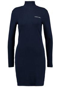 Granatowa prążkowana sukienka z długim rękawem i wysokim dekoltem, z małym białym logo "Tommy Jeans" na piersi oraz dopasowanym krojem.