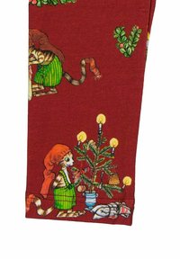 Punainen kangas, jossa on leikkisiä kuvitettuja kissoja vihreissä asuissa, koristeltuna joulukuusella, kynttilöillä ja juhlavilla koristeilla.