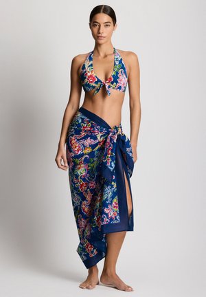 Bikini z odsłaniającym szyję fasonem w kwiatowy wzór z różowymi, zielonymi i białymi elementami na granatowym tle, w komplecie z dopasowaną spódnicą na zakładkę.