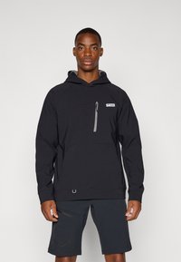 Black pullover hoodie with a grey interior, featuring a front pocket and zippered chest pocket; worn with dark shorts. Smooth texture, minimal design.