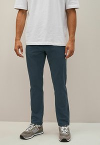 Pantaloni din bumbac de un albastru deschis, cu o croială slim, având o textură netedă. Asortați cu adidași gri și albi, cu șireturi și detalii cu logo.