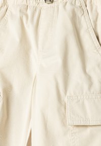 Beige cargo shorts lavet af letvægtsstof. Har en elastisk talje, sidelommer og en lomme på låret. Glat tekstur.