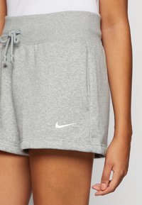 Szürke sportos rövidnadrág, puha anyagból készült. Rugalmas derékrész, húzózsinórral. Oldalsó zsebekkel rendelkezik, és fehér Nike logó található az alján.