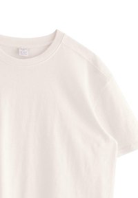 T-shirt in cotone beige chiaro con scollo rotondo e maniche corte. Presenta una vestibilità rilassata e cuciture minime, offrendo una texture liscia.