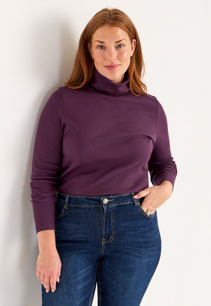 Purple turtleneck sweater with long sleeves paired with blue jeans. The sweater has a smooth texture and a fitted design.