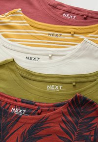 Fem crew-neck T-shirts i olika färger: vinröd, gul med ränder, gräddfärgad, olivgrön och röd med palmbladsmönster. Etiketter synliga.