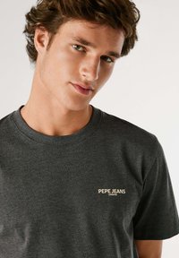Donkergrijze T-shirt met korte mouwen van katoen, met een ronde hals en een klein beige logo "PEPE JEANS LONDON" aan de linkerzijde.