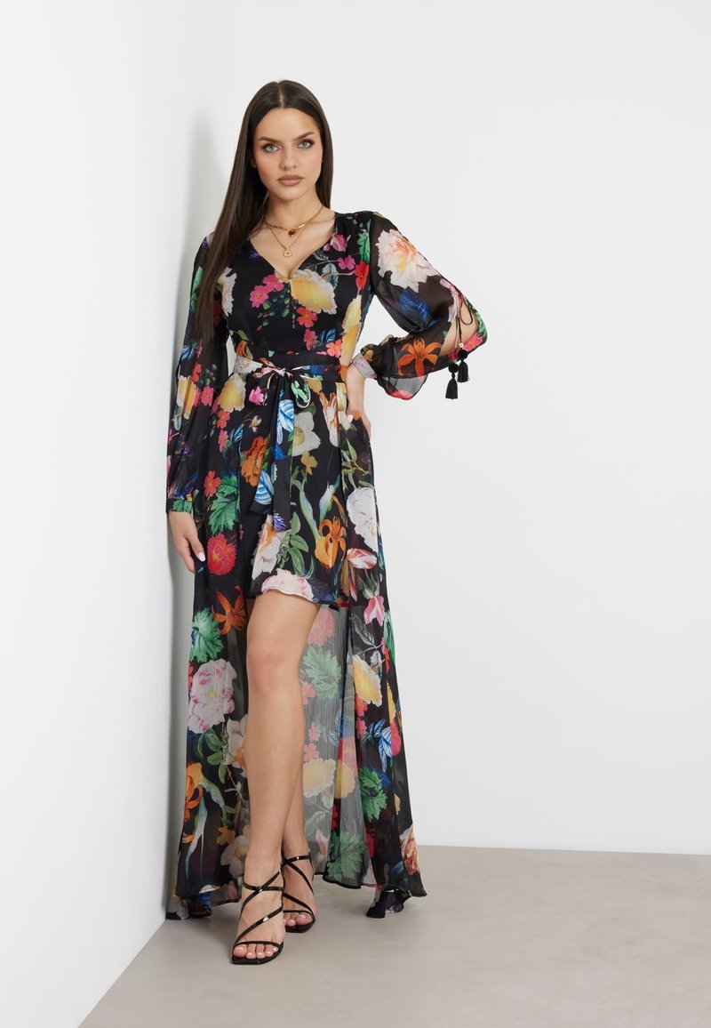 Rochie maxi neagră cu flori, cu mâneci lungi și talie legată. Prezintă flori vibrante multicolore, material transparent și o fanta până la coapsă.