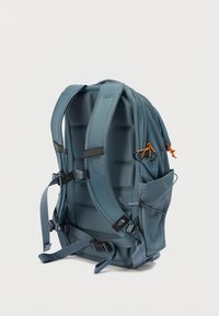 Μπλε υφασμάτινο σακίδιο με επένδυση στην πλάτη, ρυθμιζόμενους ιμάντες, πλαϊνές θήκες και πορτοκαλί διακοσμητικά στοιχεία. Κομψός, μοντέρνος σχεδιασμός με δομημένο σχήμα.