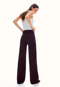 Spodnie o szerokich nogawkach w głębokim bordowym kolorze, zestawione z szarym topem bez rękawów. Spodnie mają dopasowaną talię i zwiewną fakturę.