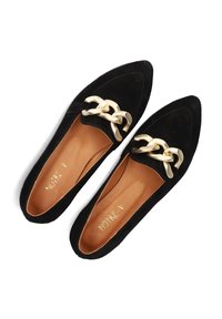 Zwarte suède ballerina's met een spitse neus, voorzien van een grote gouden kettingaccent. Het interieur is van bruin leer met een gegraveerde merknaam "NOTRE-V."