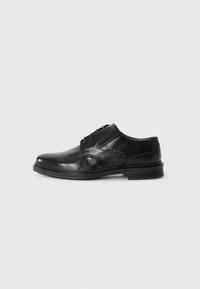 Zapato de vestir de cuero negro con un acabado suave, diseño con cordones, sutiles detalles de costura y un tacón bajo apilado.