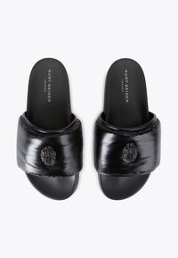 Infradito neri con un upper imbottito, caratterizzati da un emblema testurizzato. Materiale sintetico liscio con suola piatta. Nome del brand impresso all'interno.