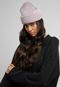 Svijetloplavi pleteni beanie s rebrastom teksturom i preklopnim rubom, koji ima malu sivu oznaku. Nosim ga uz crni oversized duksericu.