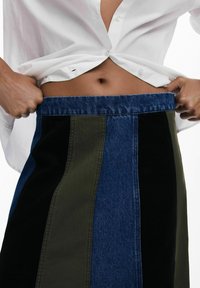 Poolside-Rock mit blauen, grünen und schwarzen vertikalen Streifen aus Denim und Cord, mit einem taillierten Bund und sichtbarem Gummiband.