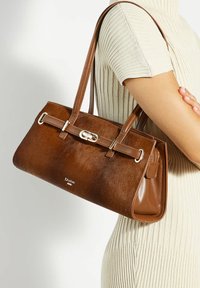 Brown handbag featuring a combination of smooth and textured leather with silver hardware and dual handles. Brand logo displayed at the front.