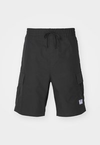 Short cargo noir avec taille élastique, cordon de serrage, poches latérales à rabat et petite étiquette blanche de marque sur l'ourlet gauche.