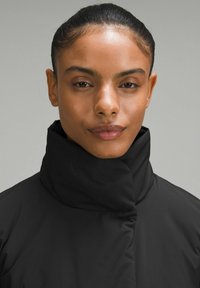 Melnas augsta apkaklīte žakete ar gludu, matētu tekstūru. Ietver slēpto rāvējslēdzēju un minimālistisku dizainu, piemērots dažādām ikdienas situācijām.